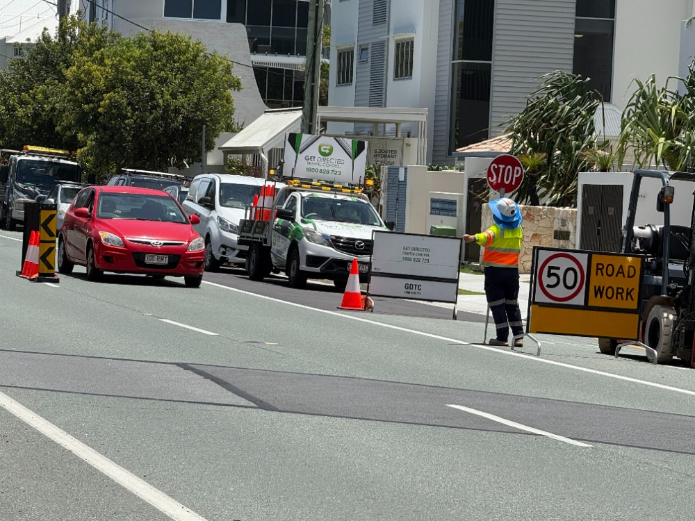Get Directed traffic controller managing a road lane closure with a stop sign
