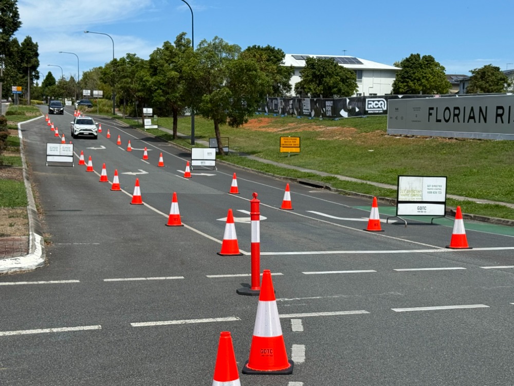 Traffic management setup with cones and signage directing vehicles through a roadwork area