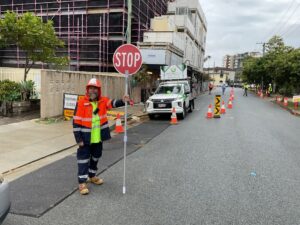 Traffic control Brisbane construction — Get Directed controller managing stop/slow operation beside urban building site.