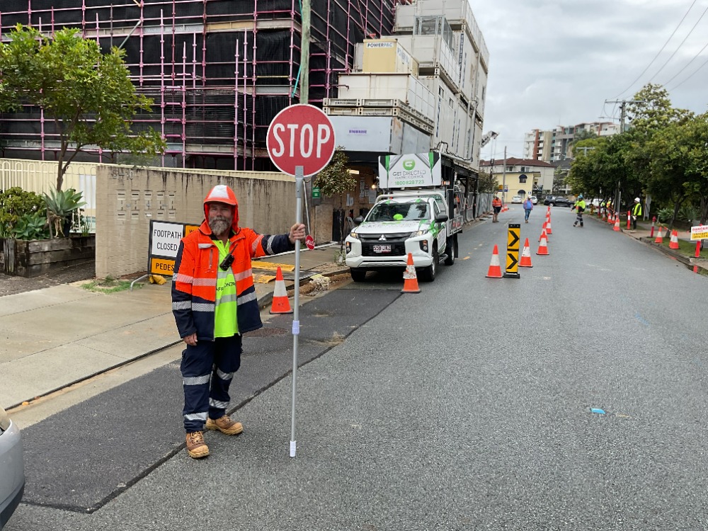 Traffic control Gold Coast construction — Get Directed controller managing stop/slow operation beside urban building site.